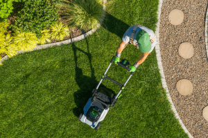 Jardinier entrain de tondre la pelouse d'un jardin