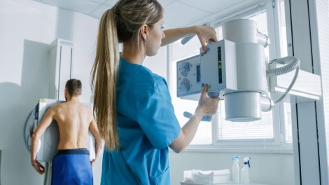Manipulateur règle la machine de radiologie pour effectuer une radio d'un patient