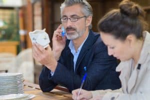 Antiquaire qui inspecte de la vaisselle en porcelaine