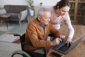 Auxiliaire de vie avec un monsieur agé dans un fauteuil roulant