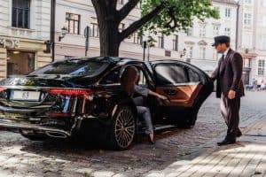 Chauffeur de maitre qui ouvre la portière à sa cliente