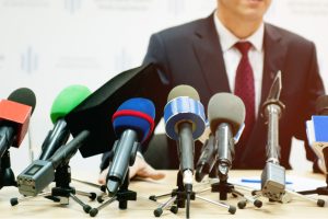 Homme parlant devant des micros lors d'une conférence de presse