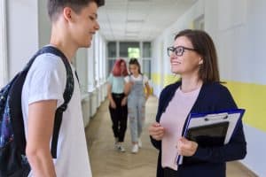 Conseillère d'insertion discute avec un adolescent dans le couloir d'une école