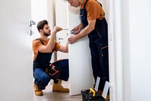 Serruriers qui posent une serrure sur une porte