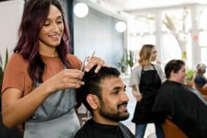 Styliste-visagiste réalise une coupe de cheveux à un homme
